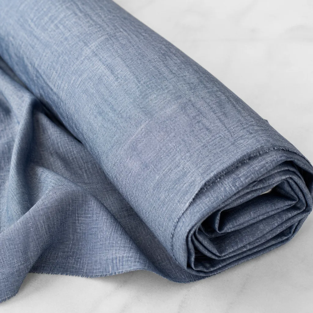 Rolled linen shirt fabric with visible natural texture on a light background